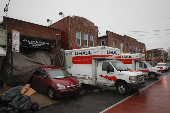 Vehicles, including two U-Haul trucks and a hearse, are parked outside Andrew T. Cleckley Funeral Home in Brooklyn. Police were called to the funeral home Wednesday after it resorted to storing dozens of bodies on ice in rented trucks. The scene was the latest example of funeral homes struggling with thousands of deaths caused by the coronavirus.